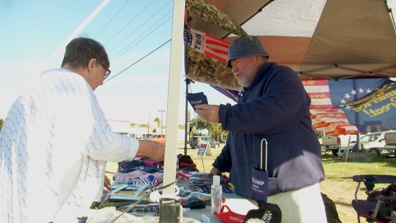 Greg Richards, right, sells Donald Trump merchandise to a customer in New Braunfels, Texas, in this image from November 2020. (Matthew Mersshon/Spectrum News 1)