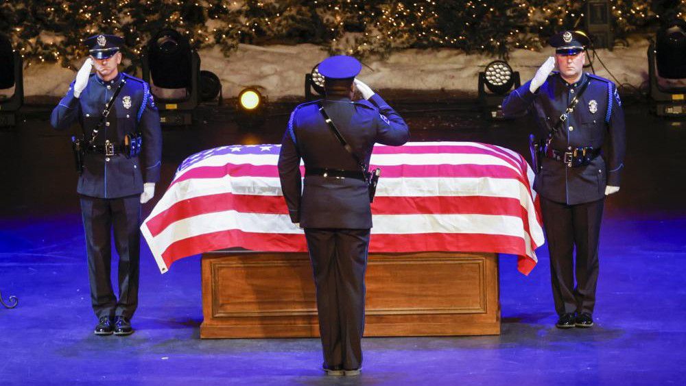 Mesquite police officers salute the casket of slain Mesquite police officer Richard Houston during a funeral at Lake Pointe Church in Rockwall, Texas on Thursday, Dec. 9, 2021. Houston was killed on Dec. 3 while responding to an altercation. (Elias Valverde II/The Dallas Morning News via AP, Pool)