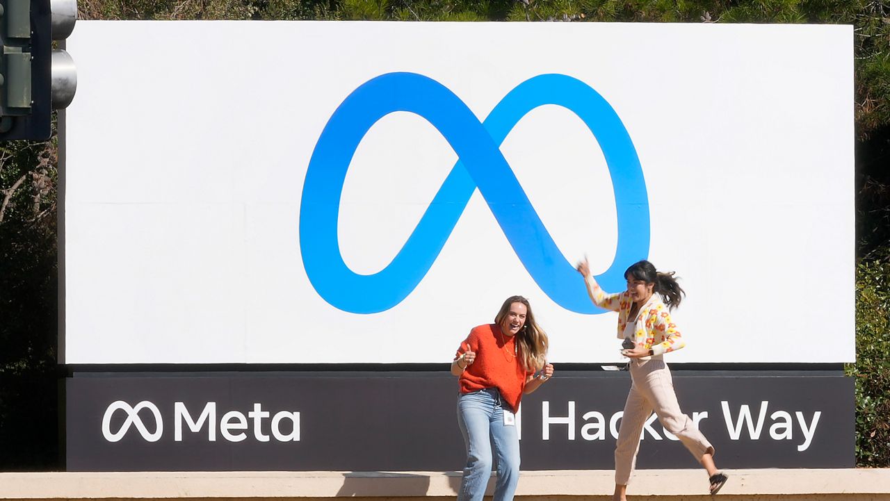 FILE - Facebook employees take a photo with the company's new name and logo outside its headquarters in Menlo Park, Calif., on Oct. 28, 2021. (AP Photo/Tony Avelar, File)