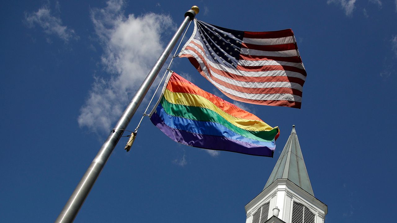 A gay Pride rainbow flag flies with the U.S. flag in front of the Asbury United Methodist Church in Prairie Village, Kan., on Friday, April 19, 2019. (AP Photo/Charlie Riedel)