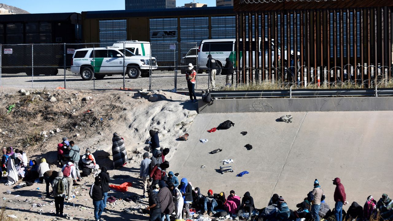 Migrants wait to cross the US-Mexico border from Ciudad Juárez, Mexico, next to U.S. Border Patrol vehicles in El Paso, Texas, Wednesday, Dec. 14, 2022. (AP Photo/Christian Chavez)