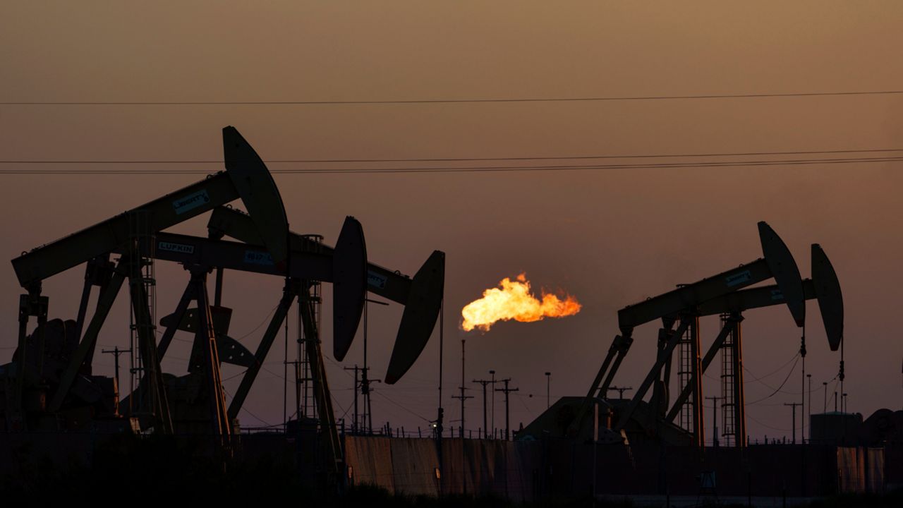 A flare burns off methane and other hydrocarbons as oil pumpjacks operate in the Permian Basin in Midland, Texas, Tuesday, Oct. 12, 2021. Massive amounts of methane are venting into the atmosphere from oil and gas operations across the Permian Basin, new aerial surveys show. The emission endanger U.S. targets for curbing climate change. (AP Photo/David Goldman)