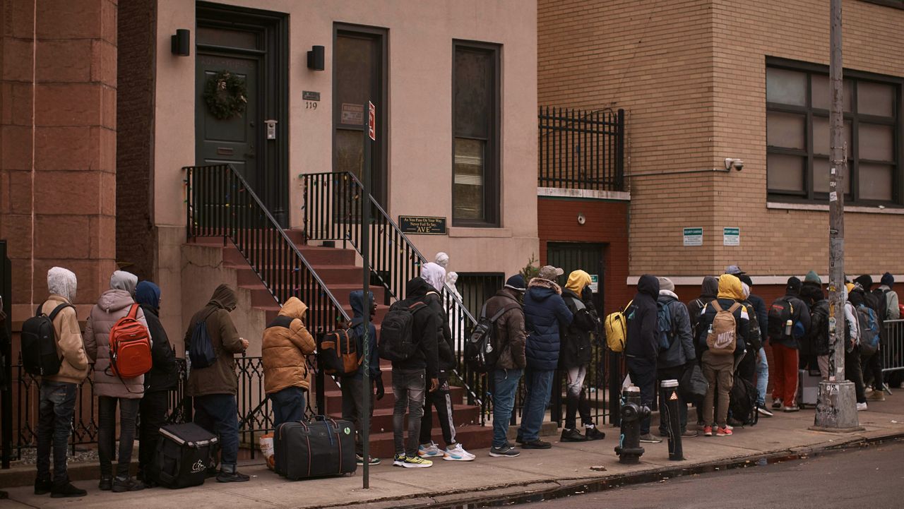 Migrants wait in the cold as they look for a shelter outside a migrant assistance center on Tuesday, Dec. 5, 2023, in New York.