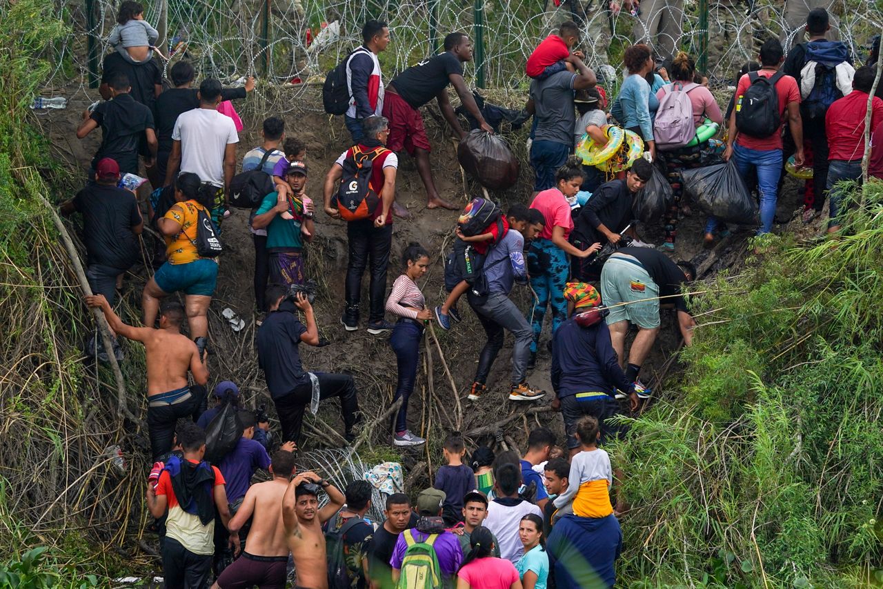 Migrants stand on the bank of the Rio Grande river as Texas National Guards block them from behind razor wire on May 11, 2023. (Fernando Llano/AP)