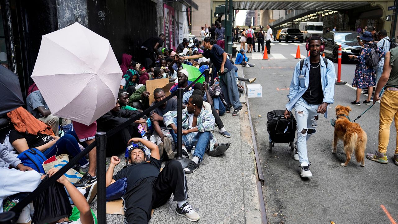 Migrants sit in a queue outside of The Roosevelt Hotel that is being used by the city as temporary housing on Monday, July 31, 2023 in New York.