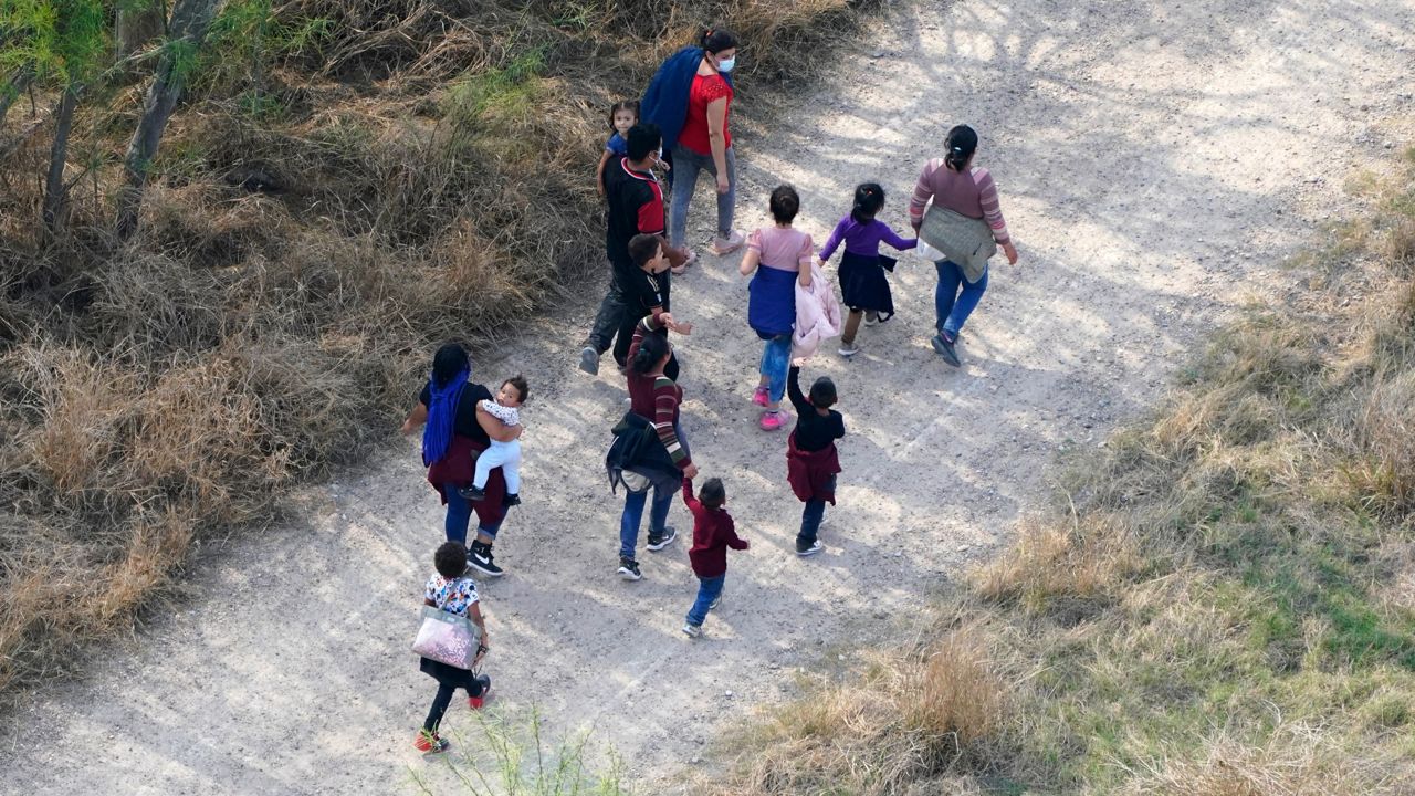 Migrants walk on a dirt road after crossing the U.S.-Mexico border, Tuesday, March 23, 2021, in Mission, Texas. (AP Photo/Julio Cortez)