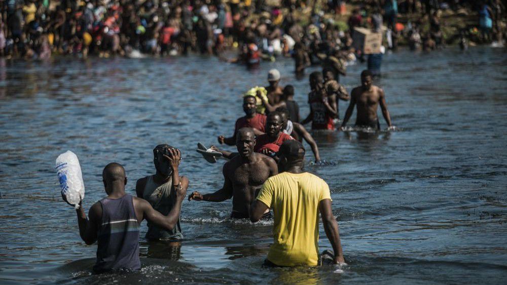 Migrants wade across the Rio Grande from Del Rio, Texas, to Ciudad Acuña, Mexico, to shop for food and supplies before returning back to the US side of the border, Sunday, Sept. 19, 2021. Thousands of Haitian migrants have been arriving to Del Rio, Texas, as authorities attempt to close the border to stop the flow of migrants. (AP Photo/Felix Marquez)