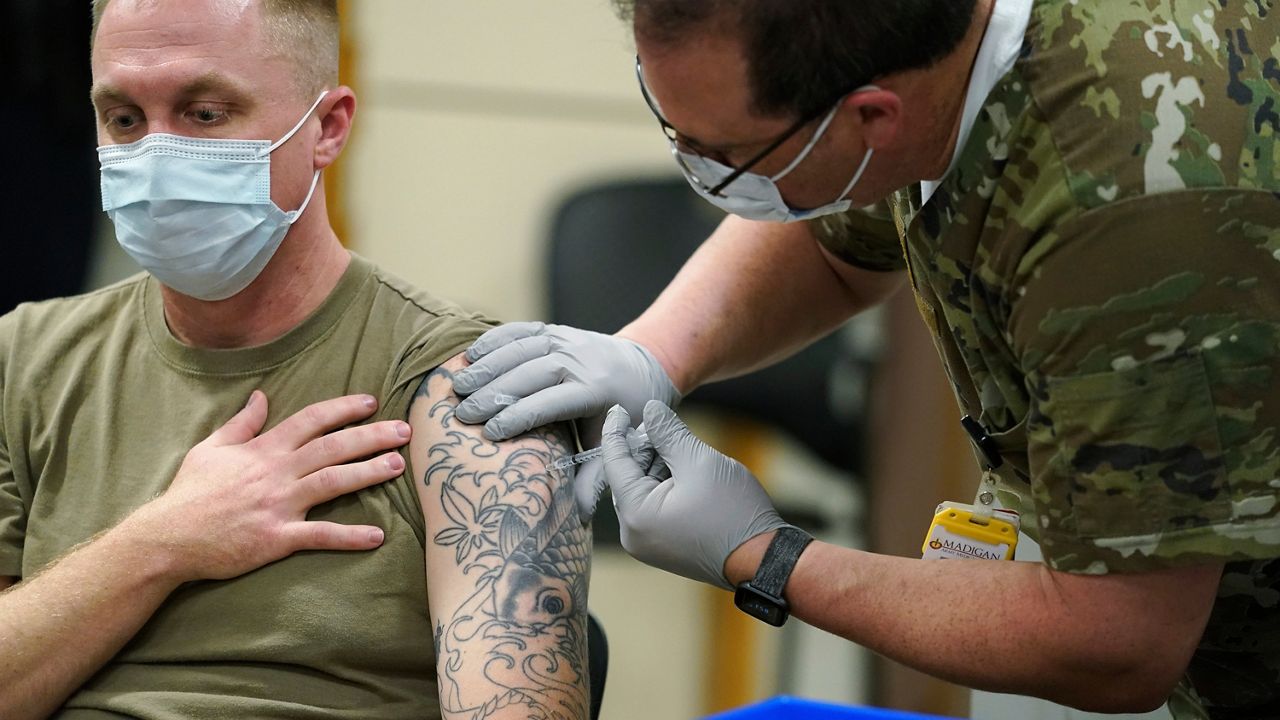 Staff Sgt. Travis Snyder, left, receives the first dose of the Pfizer COVID-19 vaccine given at Madigan Army Medical Center at Joint Base Lewis-McChord in Washington state, Dec. 16, 2020, south of Seattle. (AP Photo/Ted S. Warren)