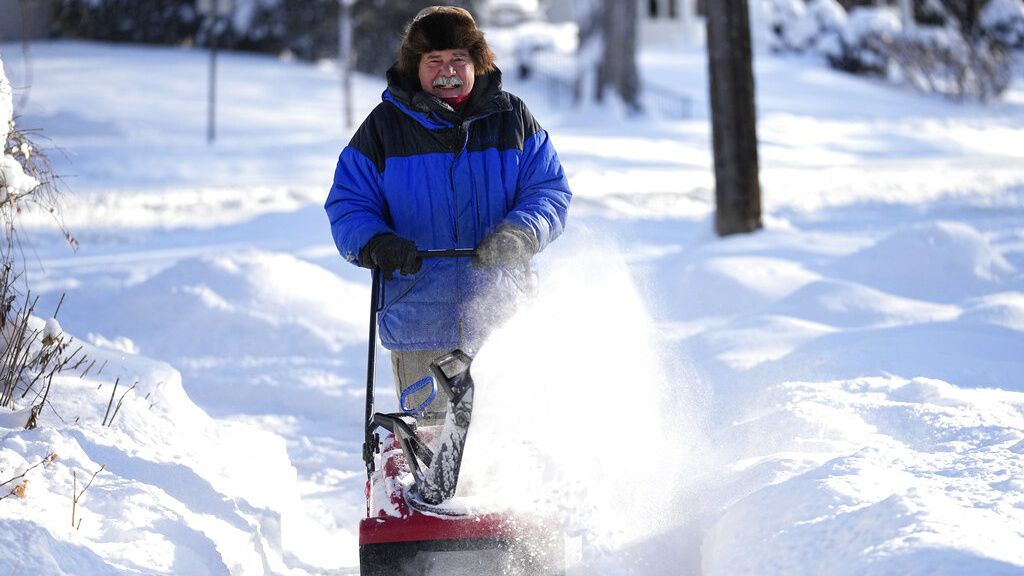 A man clears snow off a sidewalk Thursday, Dec. 22, 2022, in Minneapolis. (AP Photo/Abbie Parr)