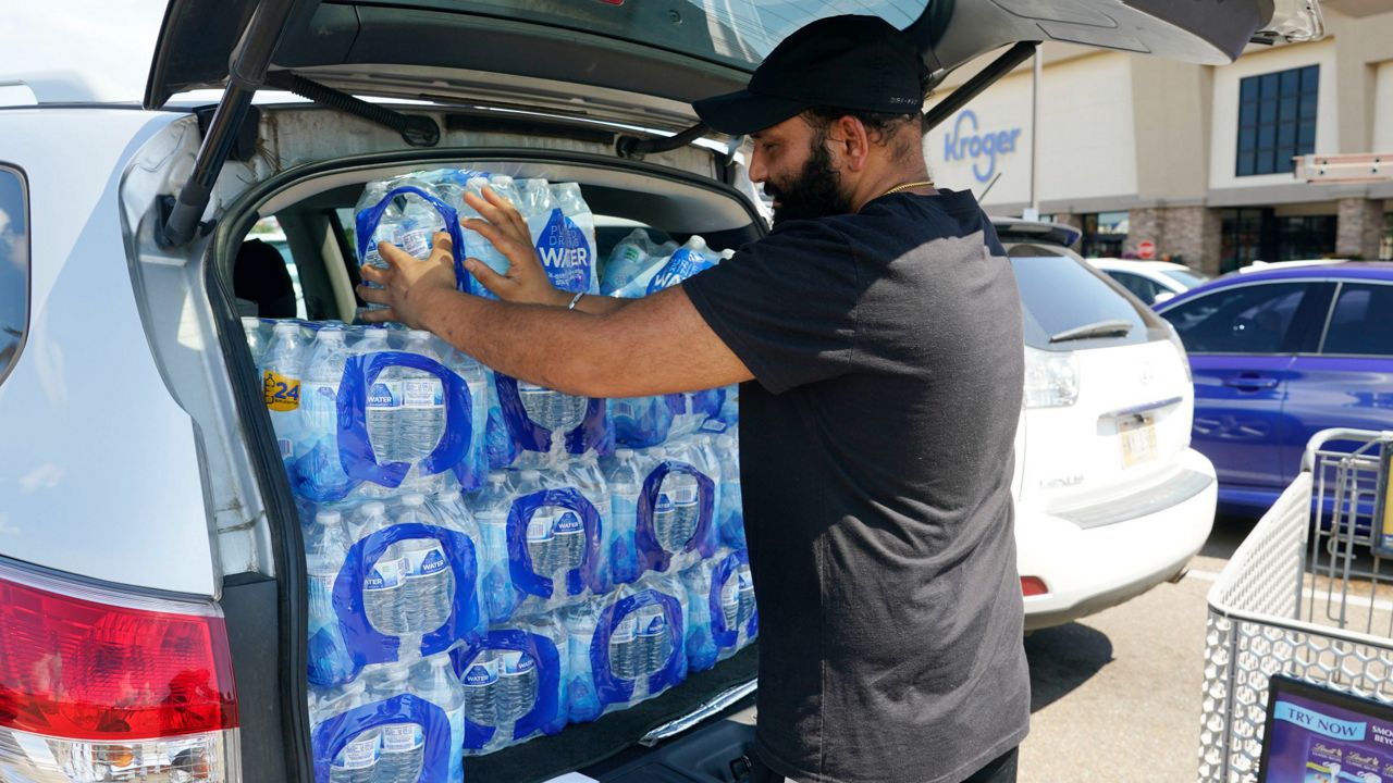 Rajwinder Singh, a gas station/convenience store owner, pats into place the 15 cases of drinking water he purchased from a Kroger grocery store into his vehicle Tuesday in Jackson, Miss. (AP Photo/Rogelio V. Solis)