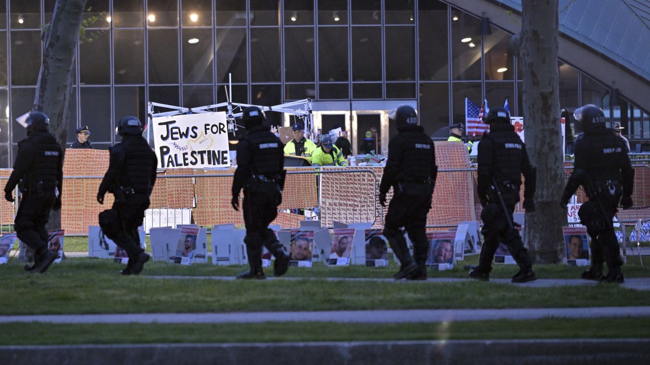 A line of police in riot gear walk past police dismantling pro-Palestinian encampment at MIT, before dawn Friday, May 10, 2024, in Cambridge, Mass. (AP Photo/Josh Reynolds)