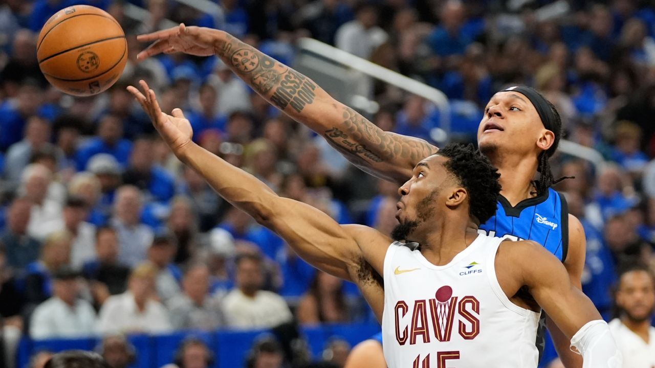 Cleveland Cavaliers guard Donovan Mitchell (45) and Orlando Magic forward Paolo Banchero, right, go after a rebound during the first half of Game 6 of an NBA basketball first-round playoff series, Friday, May 3, 2024, in Orlando, Fla.