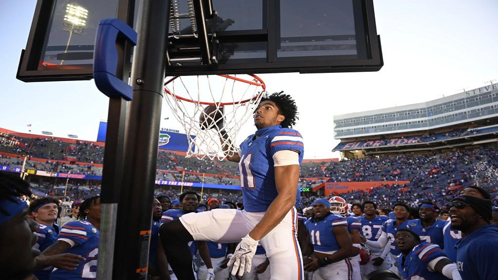 Florida wide receiver Aidan Mizell (11) performs a celebratory dunk using a basketball backboard placed on the Mississippi sideline after their 24-17 win in an NCAA college football game, Saturday, Nov. 23, 2024, in Gainesville, Fla. (AP Photo/Phelan M. Ebenhack)