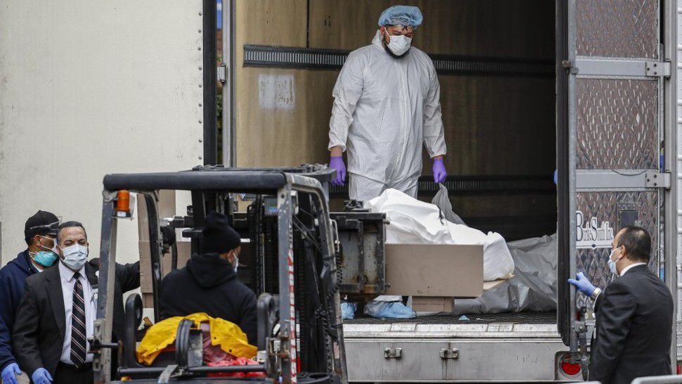 A body wrapped in plastic is loaded onto a refrigerated container truck used as a temporary morgue by medical workers wearing personal protective equipment due to COVID-19 concerns, Tuesday, March 31, 2020, at Brooklyn Hospital Center in the Brooklyn borough of New York. The new coronavirus causes mild or moderate symptoms for most people, but for some, especially older adults and people with existing health problems, it can cause more severe illness or death. (AP Photo/John Minchillo)