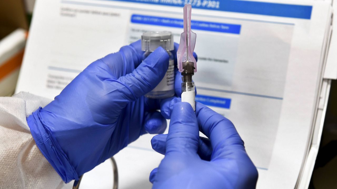 In this Monday, July 27, 2020 file photo, a nurse prepares a syringe during a study of a possible COVID-19 vaccine, developed by the National Institutes of Health and Moderna Inc., in Binghamton, N.Y. (AP Photo/Hans Pennink)