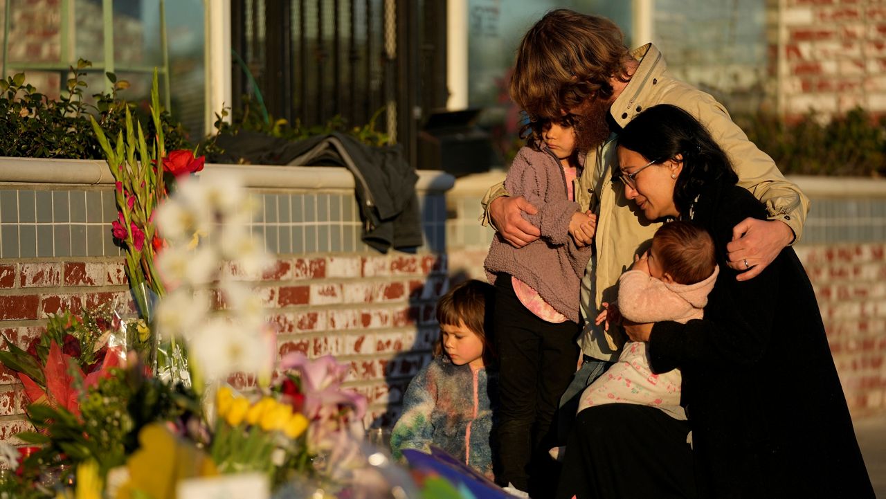 A family gathers at a memorial outside the Star Ballroom Dance Studio, the site of a mass shooting, on Tuesday, Jan. 24, 2023, in Monterey Park, Calif. (AP Photo/Ashley Landis, File)