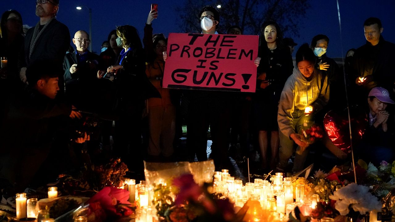 A man holds a sign during a vigil outside Monterey Park City Hall, blocks from the Star Ballroom Dance Studio, late Tuesday, Jan. 24, 2023, in Monterey Park, Calif. (AP Photo/Ashley Landis)