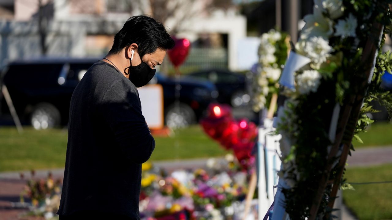 A man pauses near wooden hearts representing victims outside Monterey Park City Hall, blocks from the Star Ballroom Dance Studio on Tuesday, Jan. 24, 2023, in Monterey Park, Calif.  (AP Photo/Ashley Landis)
