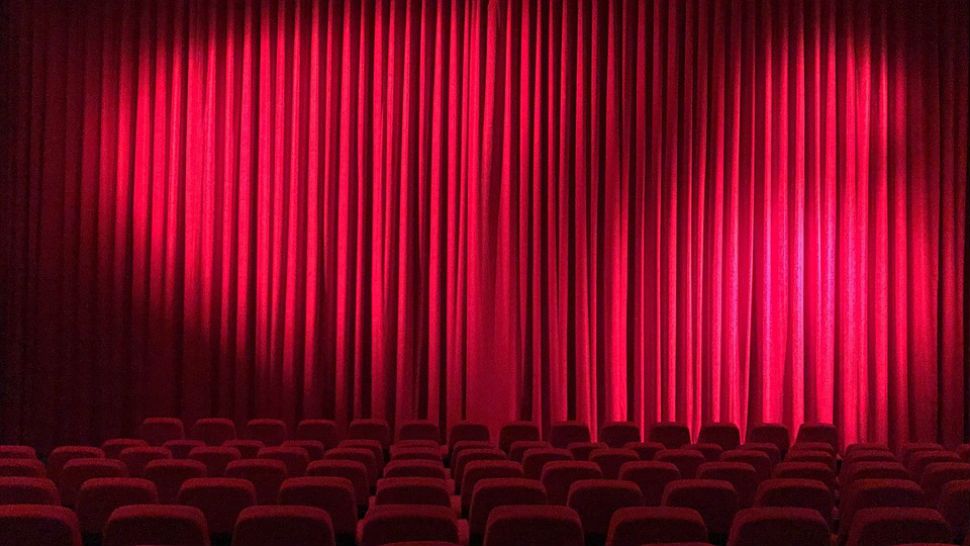 File photo of an empty movie theater with a red curtain in front of the screen. 
