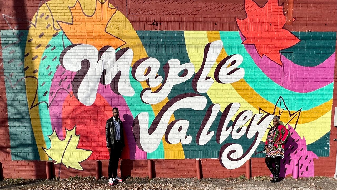 Great Streets administrator Mark Greer and Maple Valley Merchants Assoc.’s President Fannette Morris show off a new mural by the Art Bomb Brigade.