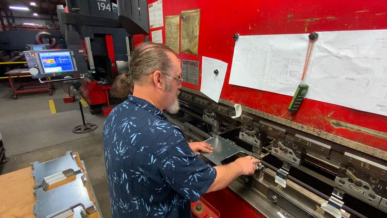John Shafer forms a piece of metal on a brake press at Muza Metal Products in Oshkosh, Wisconsin.