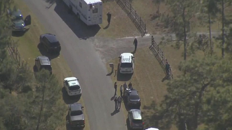 Investigators are seen outside the Chuluota home where 3 people were found dead January 25. (Sky 13)