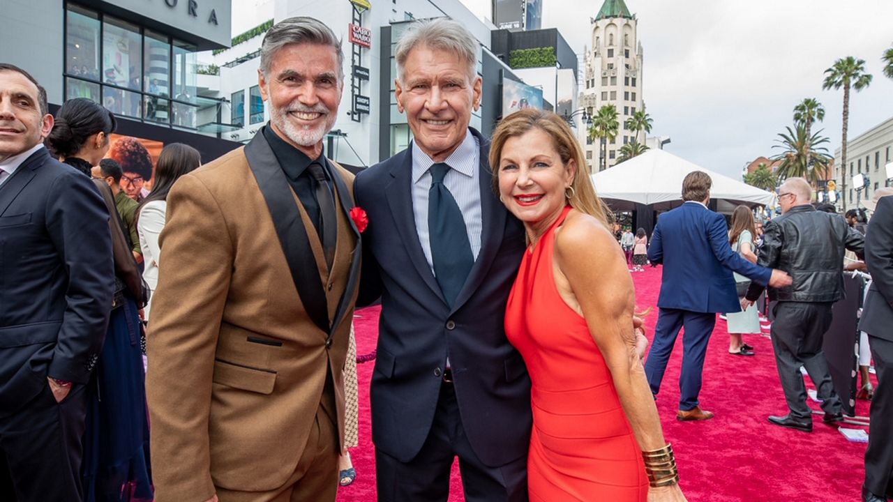 Kevin Brassard, left, and Michele Waitman, right, meet Harrison Ford at the Hollywood premiere of "Indiana Jones and the Dial of Destiny." (Photo: Disney)
