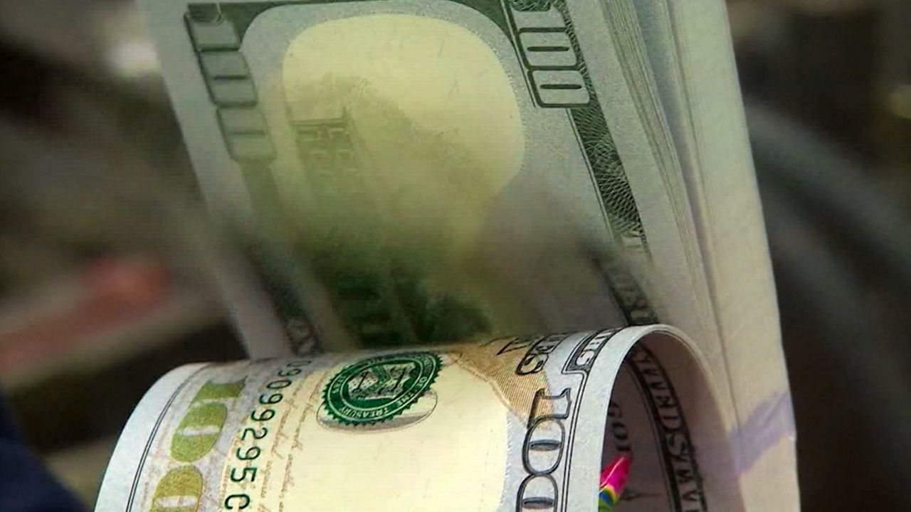 A person counts $100 bills. (Spectrum News 1/File)