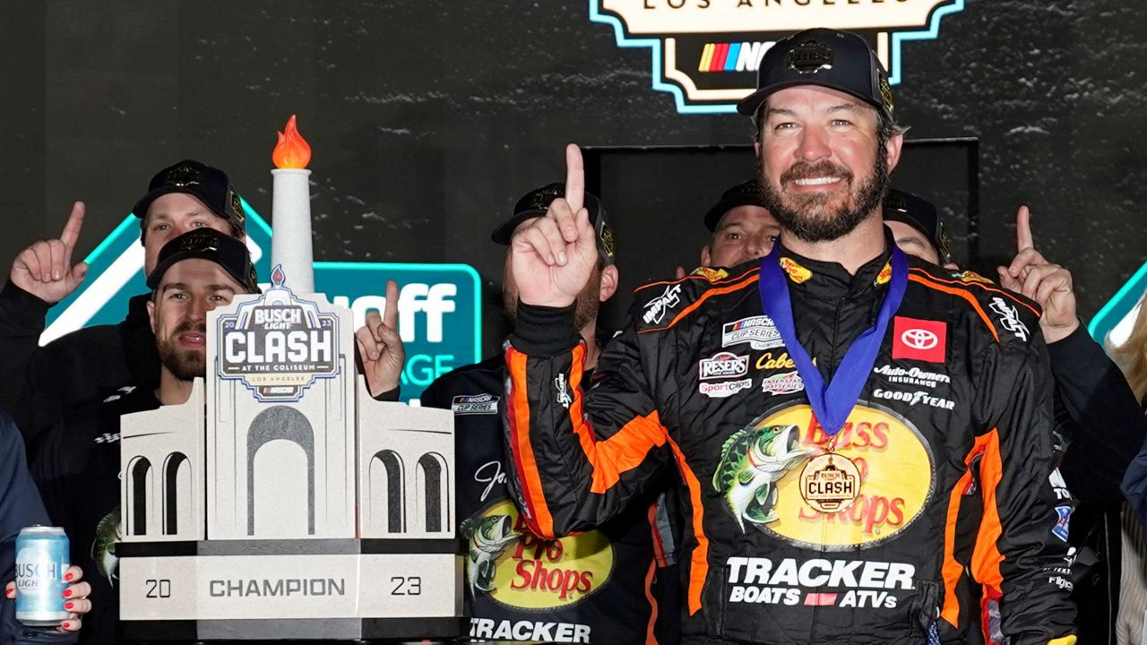 NASCAR Cup Series driver Martin Truex Jr. (19) poses for a photo with the championship trophy after winning a NASCAR exhibition auto race at Los Angeles Memorial Coliseum, Sunday, Feb. 5, 2023, in Los Angeles. (AP Photo/Ashley Landis)