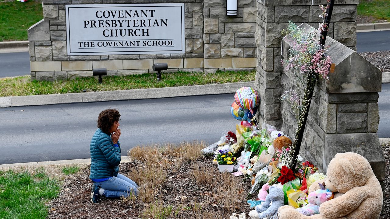 Robin Wolfeden prays in front of a makeshift memorial at the entrance to The Covenant School Tuesday, March 28, 2023, in Nashville, Tenn. Three children and three school staff members were killed by a former student in Monday's mass shooting. (Mark Zaleski /The Tennessean via AP)