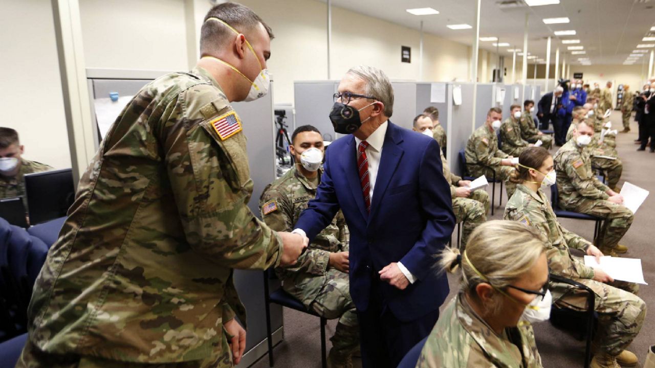 Ohio Gov. Mike DeWine shakes, right, hands with specialist Eric Lamb during a tour of the Defense Supply Center Columbus in Columbus, Ohio, as members of the Ohio Army National Guard prepare to deploy to aid Ohio hospitals during the current surge in Covid-19 hospitalizations Thursday, Jan. 6, 2022. (AP Photo/Paul Vernon)