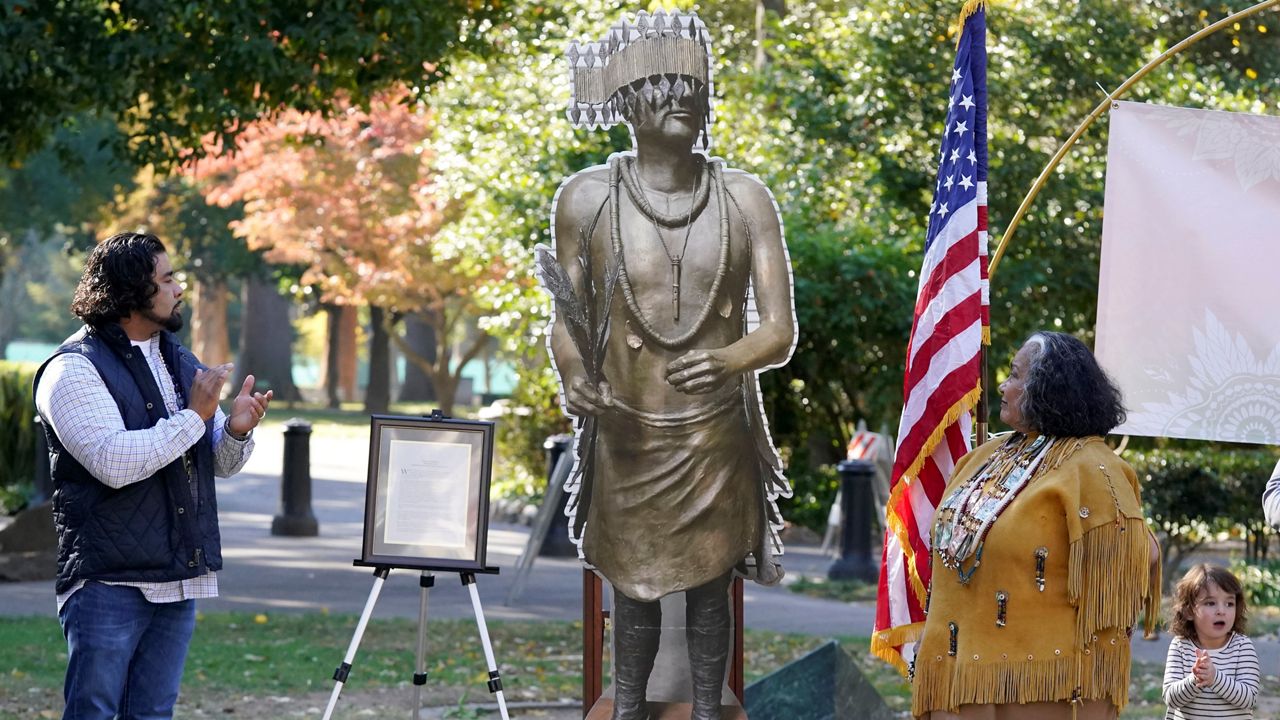 Jesse Tarango, left, chairman of Wilton Rancheria, and his mother Mary Tarango, second from right, look at an enlarged photo of a statue of the late William Franklin Sr. during a groundbreaking ceremony for a Native American monument at Capitol Park in Sacramento, Calif., Monday, Nov. 14, 2022. (AP Photo/Photo/Rich Pedroncelli)