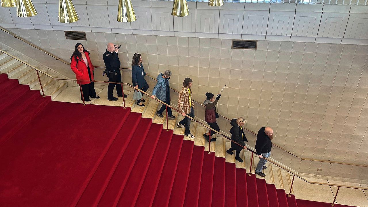 Visitors to the North Carolina Senate who are opposed to legislation that would erode the powers of the incoming governor and other elected Democrats walk along with a police officer down the stairs of the Legislative Building in Raleigh, N.C., on Monday, Dec. 2, 2024, as General Assembly police tell demonstrators to end disruptions (AP Photo/Gary D. Robertson)