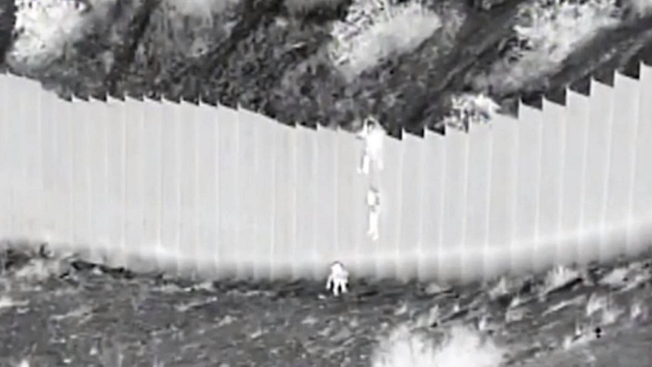 Video released Wednesday by U.S. officials shows two Ecuadoran children being dropped by smugglers over a 14-foot-high barrier along the U.S.-Mexico border.