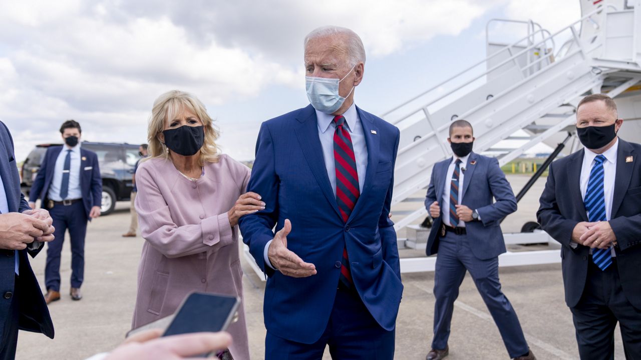 Jill Biden moves her husband, Democratic presidential candidate former Vice President Joe Biden, back from members of the media as he speaks outside his campaign plane at New Castle Airport in New Castle, Del., Monday, Oct. 5, 2020, to travel to Miami for campaign events. (AP Photo/Andrew Harnik)
