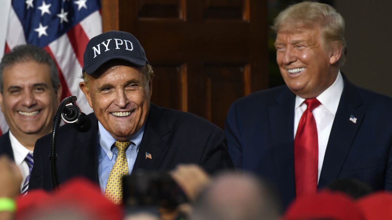 Rudy Giuliani, an attorney for President Donald Trump speaks as President Donald Trump smiles during an event Trump National Golf Club, Friday, Aug. 14, 2020, in Bedminster, N.J., with members of the City of New York Police Department Benevolent Association. (AP Photo/Susan Walsh)
