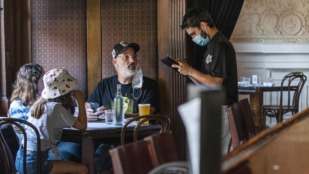 FILE - In this Sept, 4, 2020 file photo, a waiter in a protective face mask takes a customer's order during lunch at a restaurant in Hoboken, N.J. New Jersey. (AP Photo/Eduardo Munoz Alvarez, File)