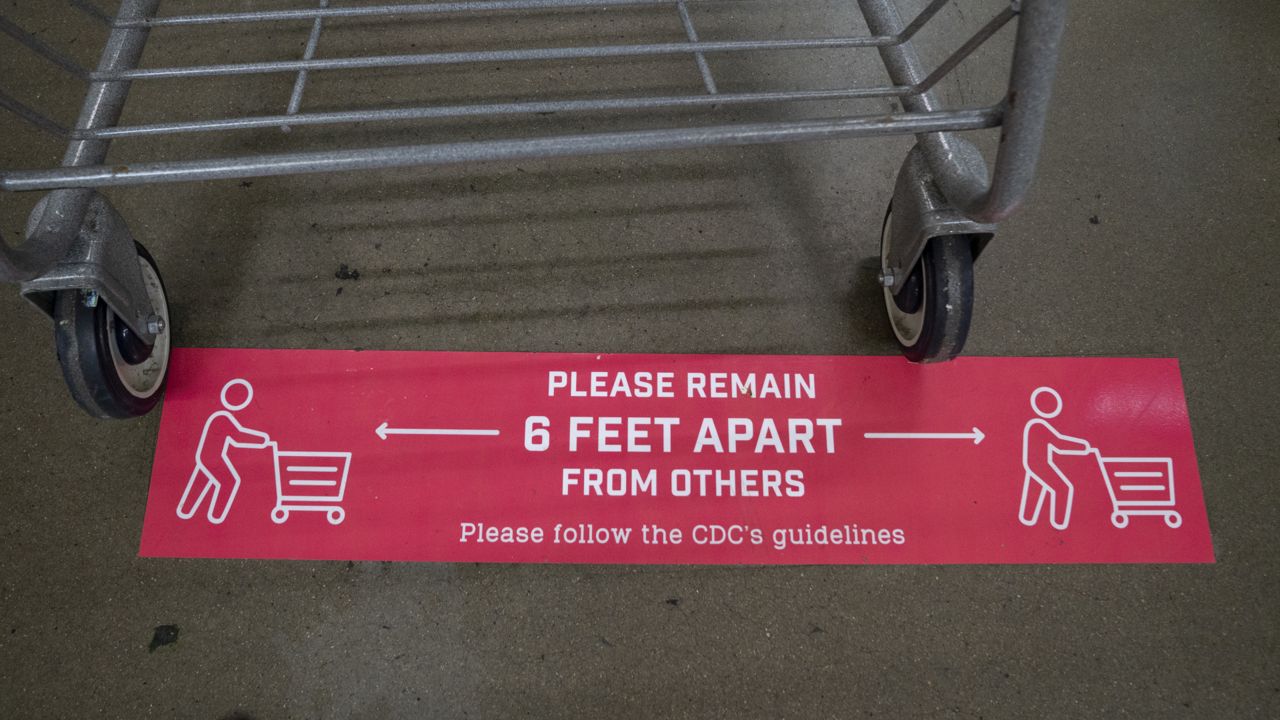 A decal showing shoppers to practice social distancing with grocery carts while shopping is posted on the floor of the checkout area in the Giant Food grocery store in Washington, Monday, June 22, 2020. (AP Photo/Carolyn Kaster)