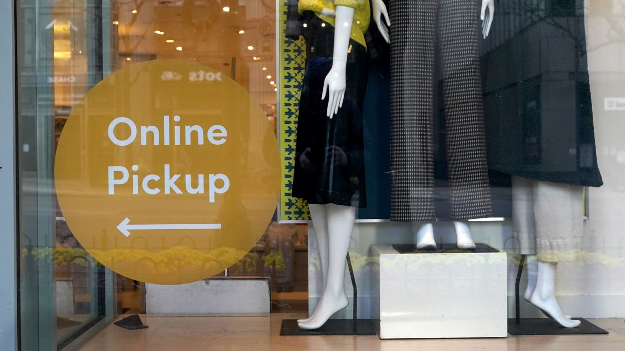 FILE: Mannequins stand on display Wednesday, Nov. 18, 2020, at the Ann Taylor store with an online pickup sign on Michigan Avenue in Chicago. (AP Photo/Charles Rex Arbogast)