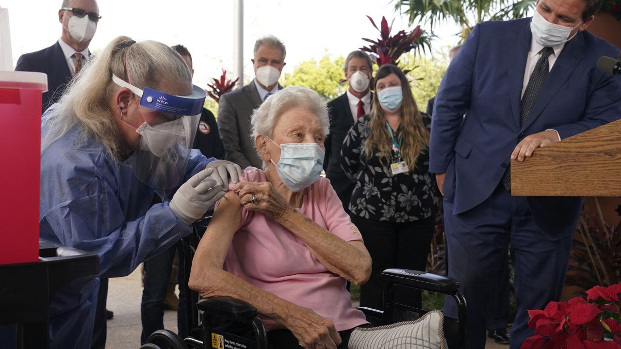 Florida Gov. Ron DeSantis watches as nurse Christine Philips, left, administers the Pfizer-BioNTech vaccine for COVID-19 to Vera Leip, 88, a resident of John Knox Village, Wednesday, Dec. 16, 2020, in Pompano Beach, Fla. (AP Photo/Marta Lavandier)