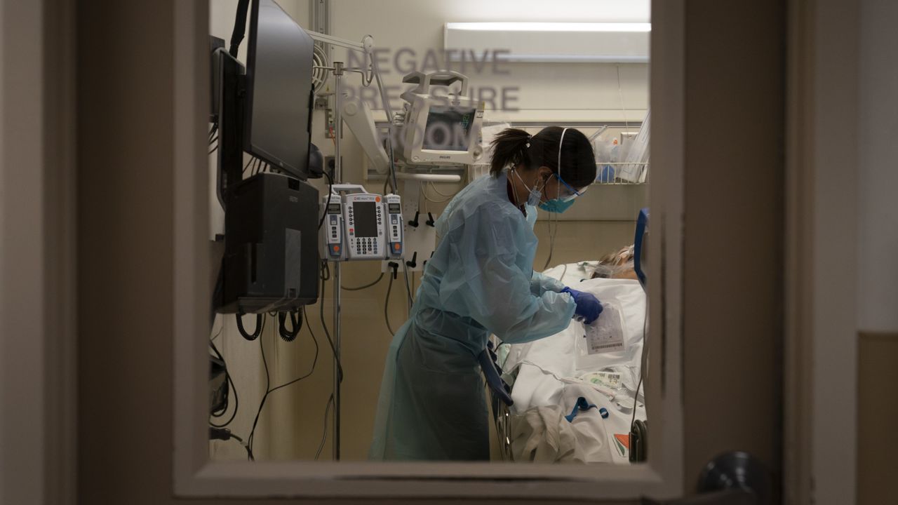 Registered nurse Darlene De Santiago tends to a COVID-19 patient in an emergency room at Providence Holy Cross Medical Center in the Mission Hills section of Los Angeles, Thursday, Nov. 19, 2020. (AP Photo/Jae C. Hong)