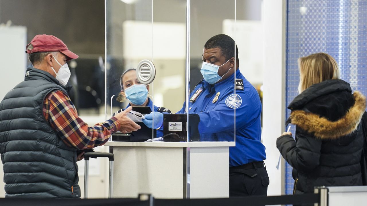 FILE: A Transportation Security Administration agent serves a traveler at a checkpoint in a sparsely populated Terminal B at LaGuardia Airport, Wednesday, Nov. 25, 2020 (AP Photo/John Minchillo)