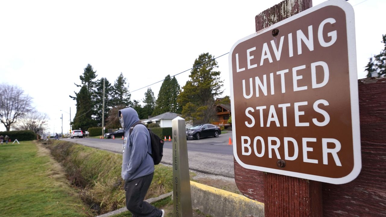 A Canadian citizen steps past a border marker and walks into the Peace Arch Historical State Park in the U.S., Sunday, Dec. 20, 2020, in Blaine, Wash. (AP Photo/Elaine Thompson)