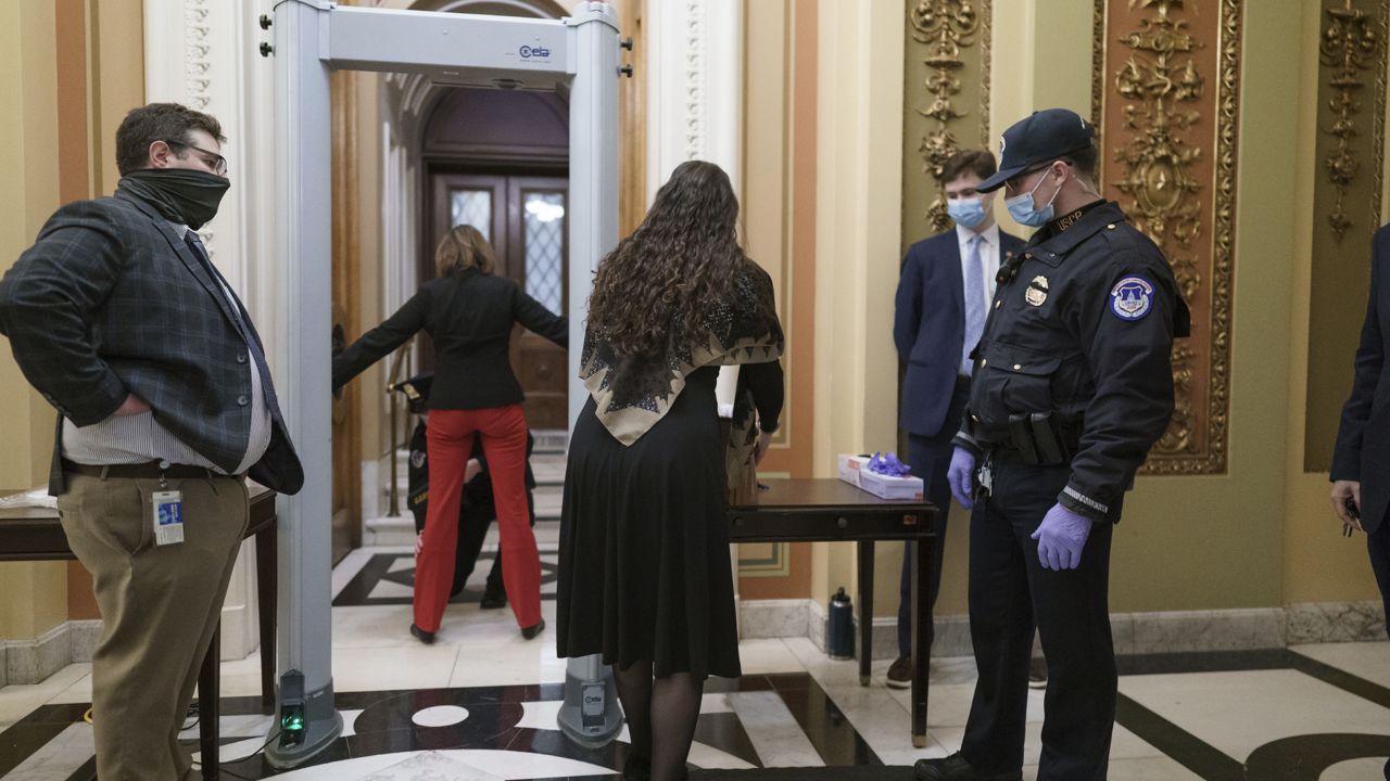 Congressional staff passes through a metal detector and security screening as they enter the House chamber, new measures put into place after a mob loyal to President Donald Trump stormed the Capitol (AP Photo/J. Scott Applewhite)