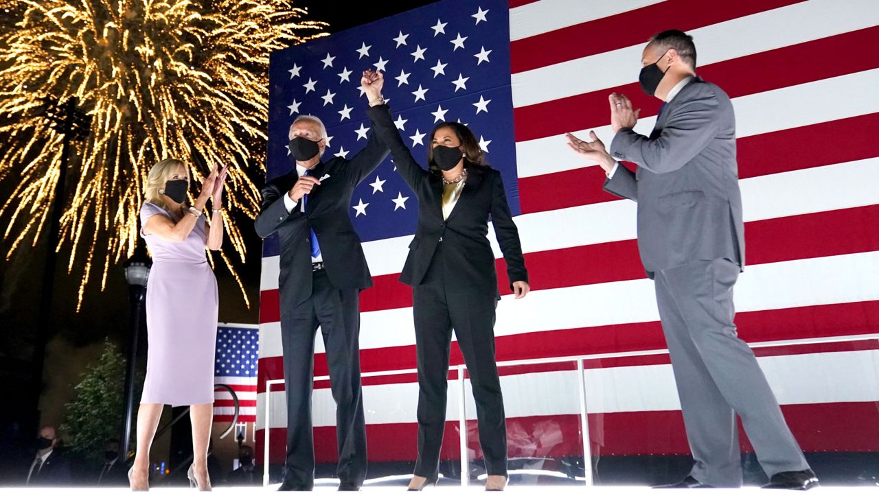 FILE: Joe Biden and Kamala Harris raise their arms up as fireworks go off in the background during the fourth day of the Democratic National Convention. (AP Photo/Andrew Harnik)