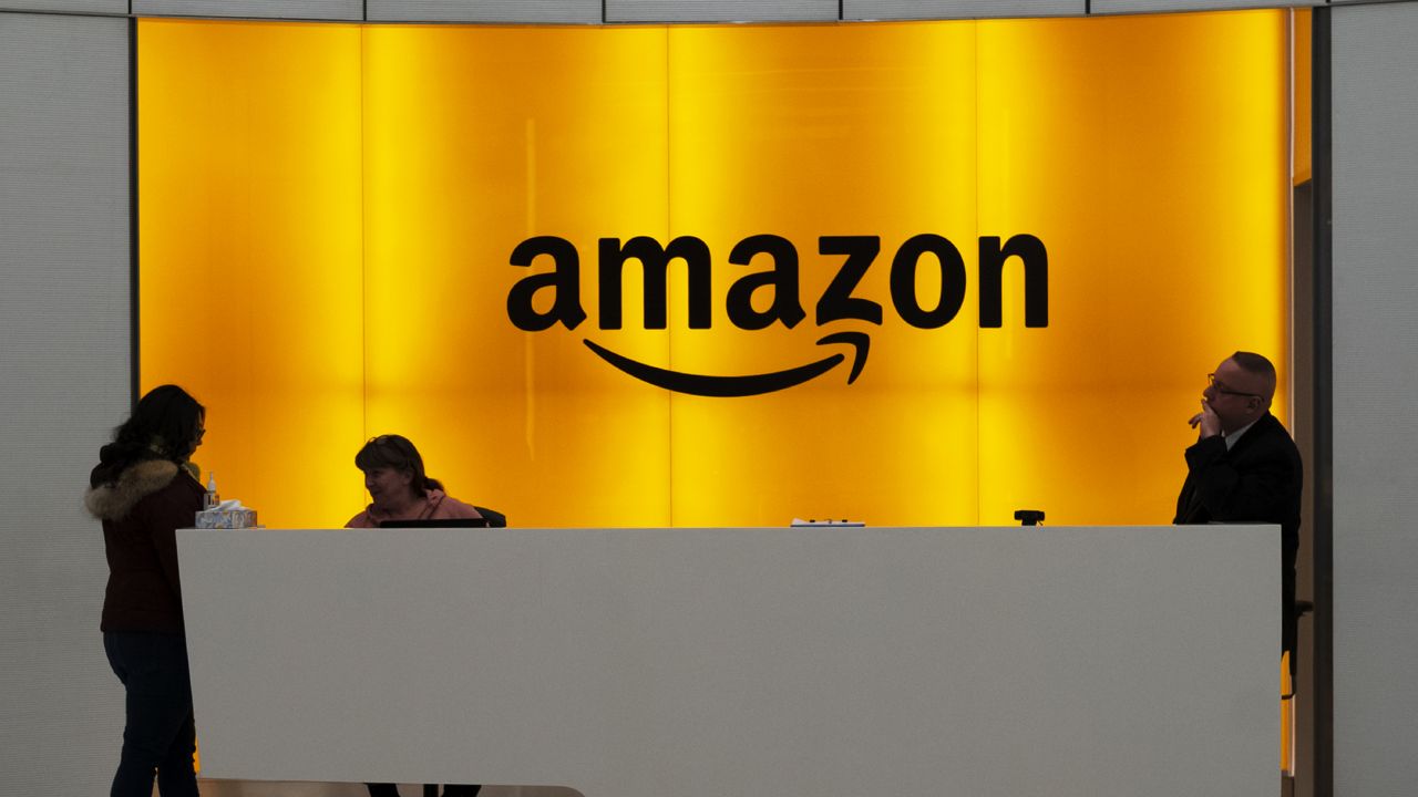 FILE - In this Feb. 14, 2019 file photo, people stand in the lobby for Amazon offices in New York. (AP Photo/Mark Lennihan, File)