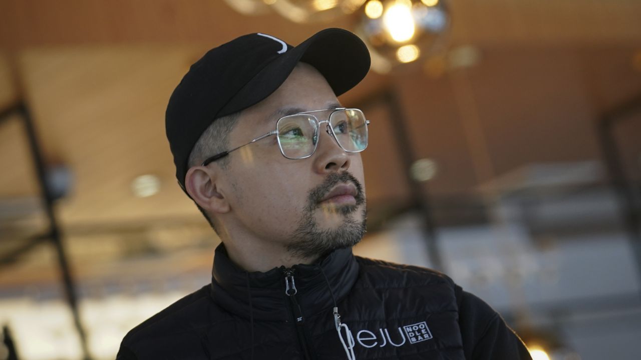 Korean American chef Douglas Kim, center, owner of the restaurant Jeju, which was vandalized during last year's racial injustice protests, is shown on the premises. (AP Photo/Bebeto Matthews)