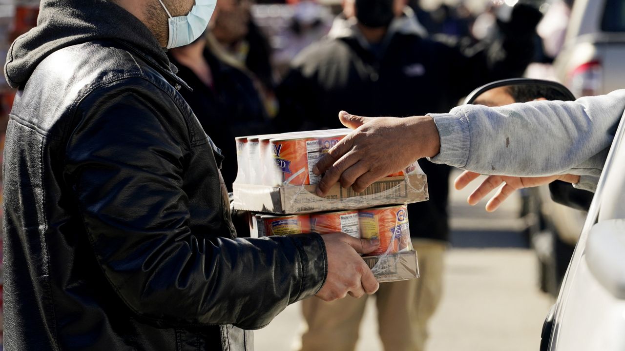 Volunteers hand out food and water at a San Antonio Food Bank drive-through food distribution site held at Rackspace Technology, Friday, Feb. 19, 2021, in San Antonio. (AP Photo/Eric Gay)