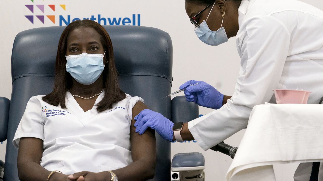 Sandra Lindsay, left, a nurse at Long Island Jewish Medical Center, is inoculated with the Pfizer-BioNTech COVID-19 vaccine by Dr. Michelle Chester, Monday, Dec. 14, 2020, in the Queens borough of New York. (AP Photo/Mark Lennihan, Pool)
