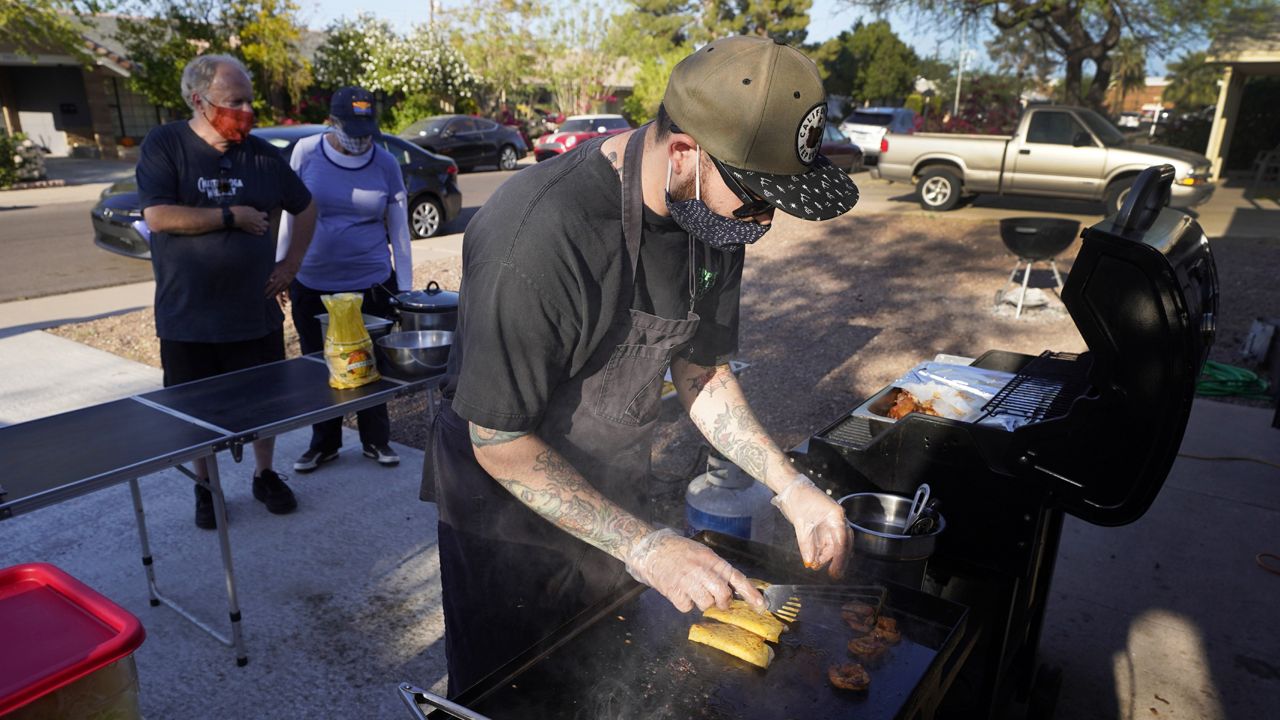 Chef Mike Winneker prepares tacos in front of his home Saturday, April 3, 2021, in Scottsdale, Ariz. (AP Photo/Ross D. Franklin)
